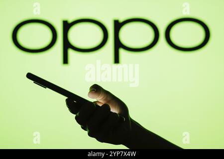 In questa immagine è raffigurato il logo OPPO sullo sfondo di una donna silhouette che tiene in mano un telefono cellulare Foto Stock
