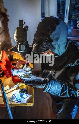 Symbolbild Wohnungseinbruch, Täter ist von der Gartenseite Her, in eine Wohnung eingedrungen und sucht nach Beute, bricht eine Geldkassette auf, findet Wertgegenstände, Geld, Einbrecher *** immagine simbolica del furto, l'esecutore ha rotto in un appartamento dal lato del giardino e sta cercando bottino, rompe apre una cassa, trova oggetti di valore, denaro Foto Stock