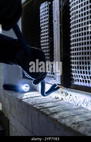 Symbolbild Wohnungseinbruch, Täter Hat sich von der Gartenseite her an ein Haus genähert und versucht ein Kellerfenster aufzubrechen um in die Wohnung zu gelangen, Einbrecher *** immagine simbolica di furto, l'autore si è avvicinato a una casa dal lato del giardino e ha cercato di aprire una finestra di cantina per entrare nell'appartamento, ladro Foto Stock