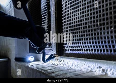Symbolbild Wohnungseinbruch, Täter Hat sich von der Gartenseite her an ein Haus genähert und versucht ein Kellerfenster aufzubrechen um in die Wohnung zu gelangen, Einbrecher *** immagine simbolica di furto, l'autore si è avvicinato a una casa dal lato del giardino e ha cercato di aprire una finestra di cantina per entrare nell'appartamento, ladro Foto Stock