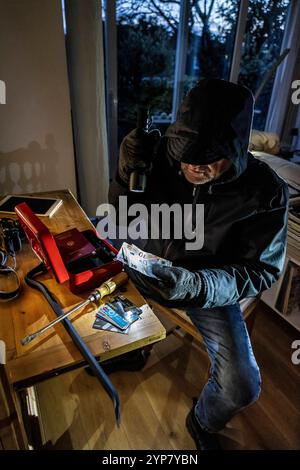 Symbolbild Wohnungseinbruch, Täter ist von der Gartenseite Her, in eine Wohnung eingedrungen und sucht nach Beute, bricht eine Geldkassette auf, findet Wertgegenstände, Geld, Einbrecher *** immagine simbolica del furto, l'esecutore ha rotto in un appartamento dal lato del giardino e sta cercando bottino, rompe apre una cassa, trova oggetti di valore, denaro Foto Stock