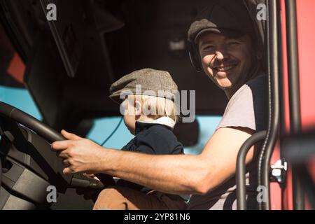 Un bambino carino che guida e' un furgone dei padri con papa' Foto Stock