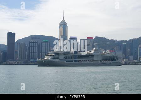 La nave da crociera Silver Nova naviga attraverso Victoria Harbour di fronte allo skyline in una giornata di sole. Hong Kong - 25 ottobre 2024 Foto Stock