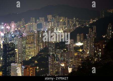Skyline di Hong Kong di notte. Vista dei grattacieli residenziali illuminati in contrasto con la montagna del Victoria Peak. Hong Kong Foto Stock