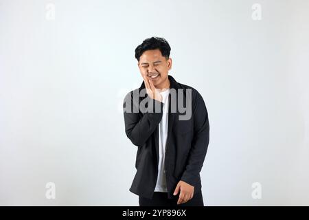 Giovane uomo asiatico in piedi su sfondo bianco toccando bocca con la mano, espressione dolorosa a causa di mal di denti o malattie dentali sui denti Foto Stock