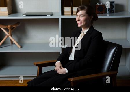 Donna d'affari seduta su una sedia rivestita in pelle Foto Stock