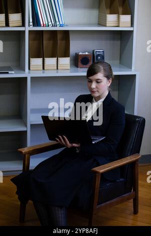 Donna d'affari seduta su una sedia rivestita in pelle Foto Stock