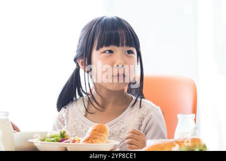 I bambini delle scuole primarie mangiano il pranzo scolastico Foto Stock