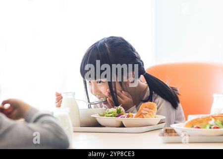 I bambini delle scuole primarie mangiano il pranzo scolastico Foto Stock