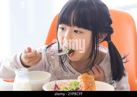 I bambini delle scuole primarie mangiano il pranzo scolastico Foto Stock