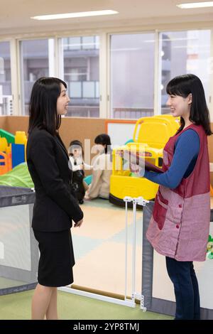 Lavoratore di assistenza all'infanzia che parla con i genitori Foto Stock