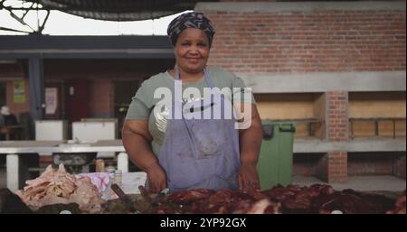 Ritratto di una macelleria africana felice che indossa un velo in un laboratorio di una township, in piedi accanto Foto Stock