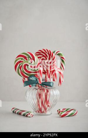 Caramelle natalizie, lecca lecca e marshmallow in vasetti di vetro su sfondo chiaro Foto Stock