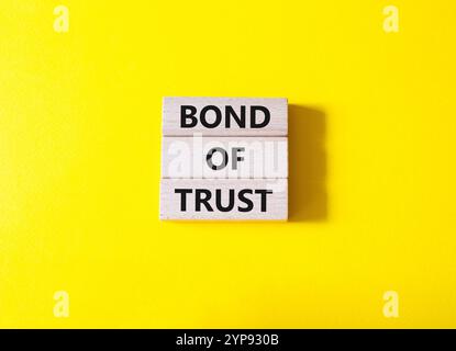 Simbolo del legame di fiducia. Blocchi di legno con parole Bond of Trust. Bellissimo sfondo giallo. Business e Bond of Trust. Copia spazio. Foto Stock