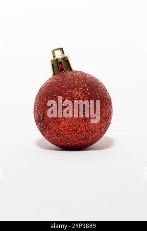 Un luccicante ornamento natalizio rosso a forma di sfera, su uno sfondo bianco e pulito. Natal Foto Stock