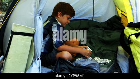 Ragazzo che gioca a carte nella tenda del campeggio Foto Stock