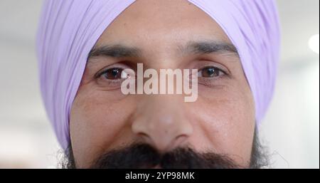 Ritratto di felice birazziale sikh maschio medico in turbante guardando la macchina fotografica in ospedale, al rallentatore Foto Stock