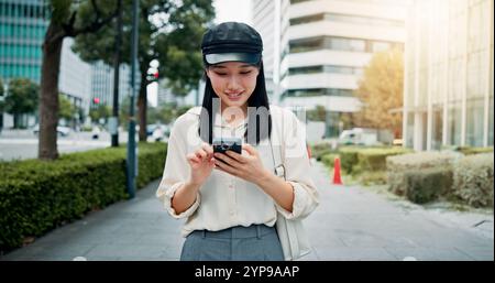 Viaggi, ricerca e donna con smartphone, città e comunicazione con opportunità di lavoro e digitazione. Esterno, a piedi e asiatico con mobile per Foto Stock