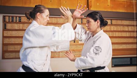 Arti marziali, dimostrazioni di lotta e donne con apprendimento, esercizio fisico e galateo di karate nel dojo. Giappone, allenamento e studio con sport, disciplina Foto Stock