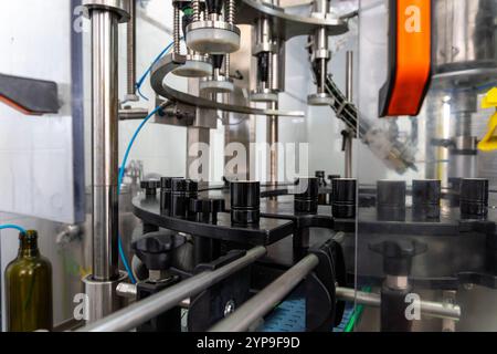 Linea di imbottigliamento automatizzata per la produzione di olio extra vergine di oliva con sistema di controllo della qualità e macchinari di precisione. Vista ravvicinata del riempimento industriale Foto Stock