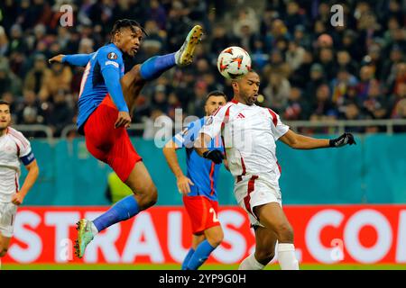 Bucarest, Romania. 28 novembre 2024. Il Siyabonga Ngezana (2° L) della FCSB affronta Ayoub El Kaabi (1° R) dell'Olympiacos durante la partita di campionato tra FCSB e Olympiacos alla partita di calcio UEFA Europa League allo stadio Arena Nationala di Bucarest, Romania, 28 novembre 2024. Crediti: Cristian Cristel/Xinhua/Alamy Live News Foto Stock