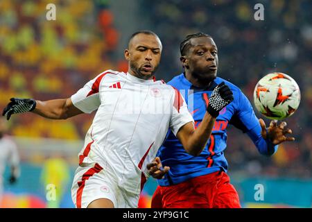 Bucarest, Romania. 28 novembre 2024. Joyskim Dawa (R) della FCSB sfida con Ayoub El Kaabi dell'Olympiacos durante la partita di campionato tra FCSB e Olympiacos alla partita di calcio UEFA Europa League allo stadio Arena Nationala di Bucarest, Romania, 28 novembre 2024. Crediti: Cristian Cristel/Xinhua/Alamy Live News Foto Stock