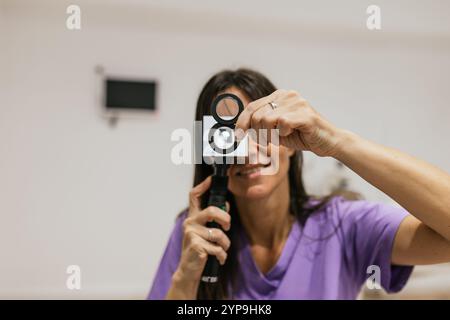 Optometrista che esegue un esame retinoscopico utilizzando il retinoscopio Foto Stock
