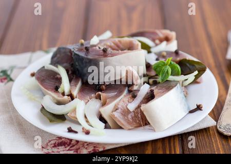 sgombro leggermente salato con cipolle e spezie, in un piatto su un tavolo di legno. Foto Stock