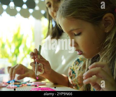 L'insegnante in officina ha messo in tecnica due ragazze come assemblare un mosaico termico Foto Stock