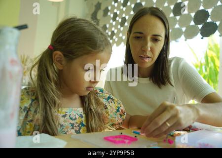 L'insegnante in officina ha messo in tecnica due ragazze come assemblare un mosaico termico Foto Stock