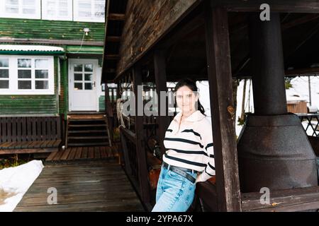 giovane donna vicino a un gazebo con grigliate davanti a una casa di legno Foto Stock