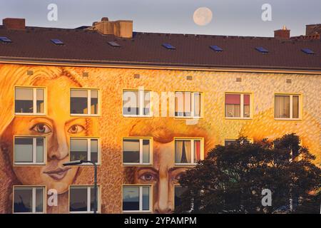 Muro di un condominio dipinto di volti alla luce della sera, Street art, con luna piena, Germania, Renania settentrionale-Vestfalia, basso Reno, Dusse Foto Stock