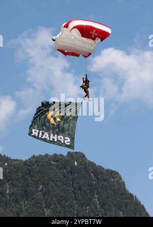 Ein Fallschirmspringer der Swiss Parawings, einem Fallschirm-Displayteams der Schweizer Armee, un einem Freifallschirm mit der Flagge SPHAIR. Hochkant. Die Flugshow ZigAirMeet mit internationaler Beteiligung aus dem militärischen und zivilen Luftfahrtbereich fand AM 18. und 19. Agosto 2023 a Mollis, Kanton Glarus, Schweiz, statt. Mollis Glarus Schweiz *** paracadutista di Swiss Parawings, un gruppo di paracadutisti delle forze Armate Svizzere, su un paracadute a caduta libera con la bandiera SPHAIR in verticale lo spettacolo aereo ZigAirMeet con la partecipazione internazionale del settore dell'aviazione militare e civile t Foto Stock