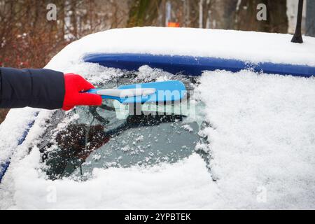 Utilizzare la spazzola manualmente e rimuovere la neve dalla vettura e dal parabrezza. Problemi invernali nel trasporto Foto Stock