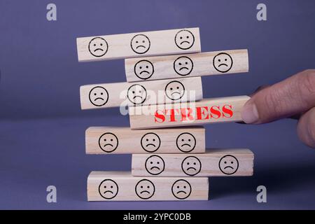 Simbolo di sollecitazione. Parola concettuale stress su blocchi di legno. Splendido sfondo grigio blu. Il concetto di faccia triste e stress. Copia spazio Foto Stock