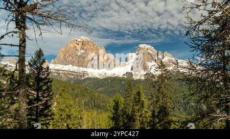Sul sentiero della Croda da Lago, il fogliame rosso e arancio ardente dell'autunno contrasta splendidamente con le aspre vette delle Dolomiti in lontananza Foto Stock