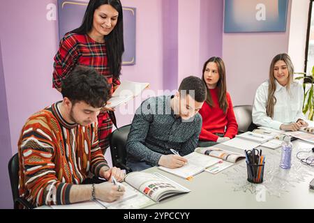 Insegnante donna che spiega il soggetto ai suoi studenti adolescenti alla scuola di lingue Foto Stock