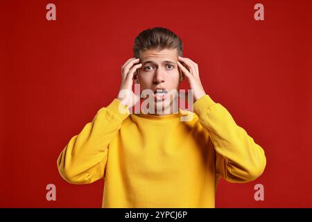 Studente emotivo che ha stress prima dell'esame su sfondo rosso Foto Stock