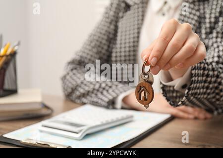 Agente immobiliare con la chiave della casa a tavola, primo piano Foto Stock