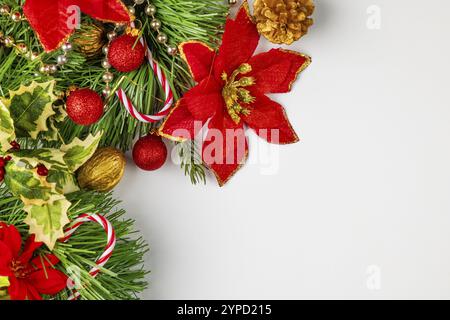 Decorazioni natalizie con fiori rossi, dolcetti, noci e bastoncini di caramelle su sfondo bianco, sala fotocopie Foto Stock