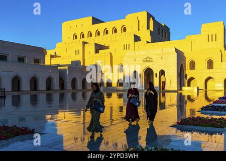 Una donna del posto in abiti tradizionali passeggia attraverso la piazza principale della Royal Opera alla luce della sera, Mascate, Penisola Araba, Sultanato dell'Oman Foto Stock