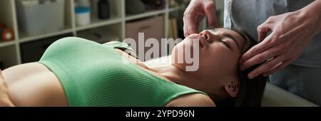Donna sdraiata sul tavolo da massaggio che prova un massaggio facciale con le mani che massaggiano le tempie. Scaffali pieni di prodotti spa sullo sfondo creano un'atmosfera tranquilla Foto Stock