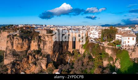 Vista aerea di Ronda, Spagna, al tramonto con il ponte Puente Nuevo su una profonda gola, circondata da scogliere, vegetazione e edificio andaluso imbiancato Foto Stock