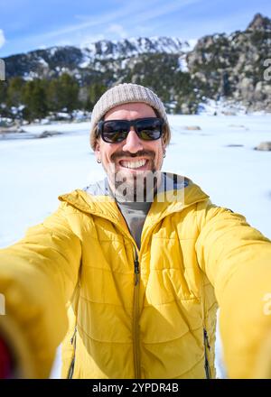 POV di un giovane uomo barbuto caucasico felice che si fa selfie con due mani e la giostrina in montagne innevate Foto Stock