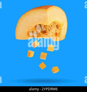 Pezzi di zucca cruda fresca che cadono su sfondo blu Foto Stock