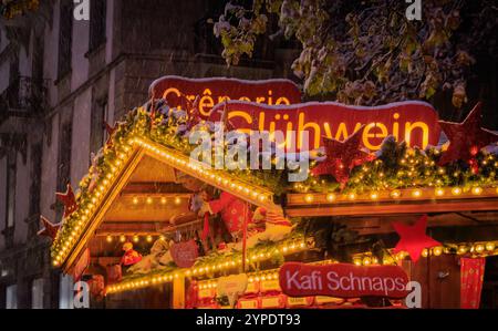 Il caldo bagliore di un'accogliente bancarella di VIN brulé con luci festose sotto la neve che cade, una scena magica al mercatino di Natale di Zurigo in Svizzera Foto Stock