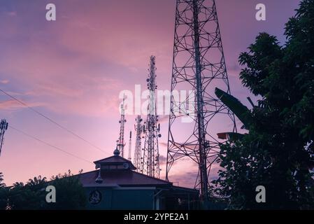 Il palo della torre BTS o il trasmettitore radio svettano in alto nel cielo al mattino Foto Stock