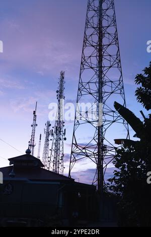 Il palo della torre BTS o il trasmettitore radio svettano in alto nel cielo al mattino Foto Stock