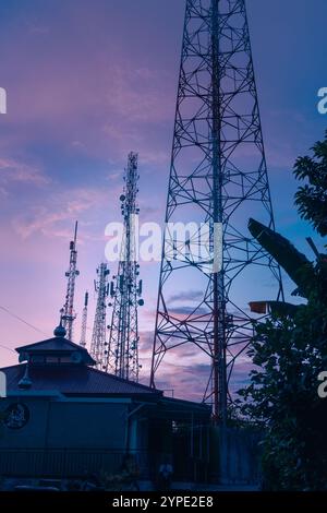 Il palo della torre BTS o il trasmettitore radio svettano in alto nel cielo al mattino Foto Stock