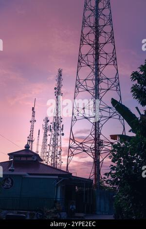 Il palo della torre BTS o il trasmettitore radio svettano in alto nel cielo al mattino Foto Stock